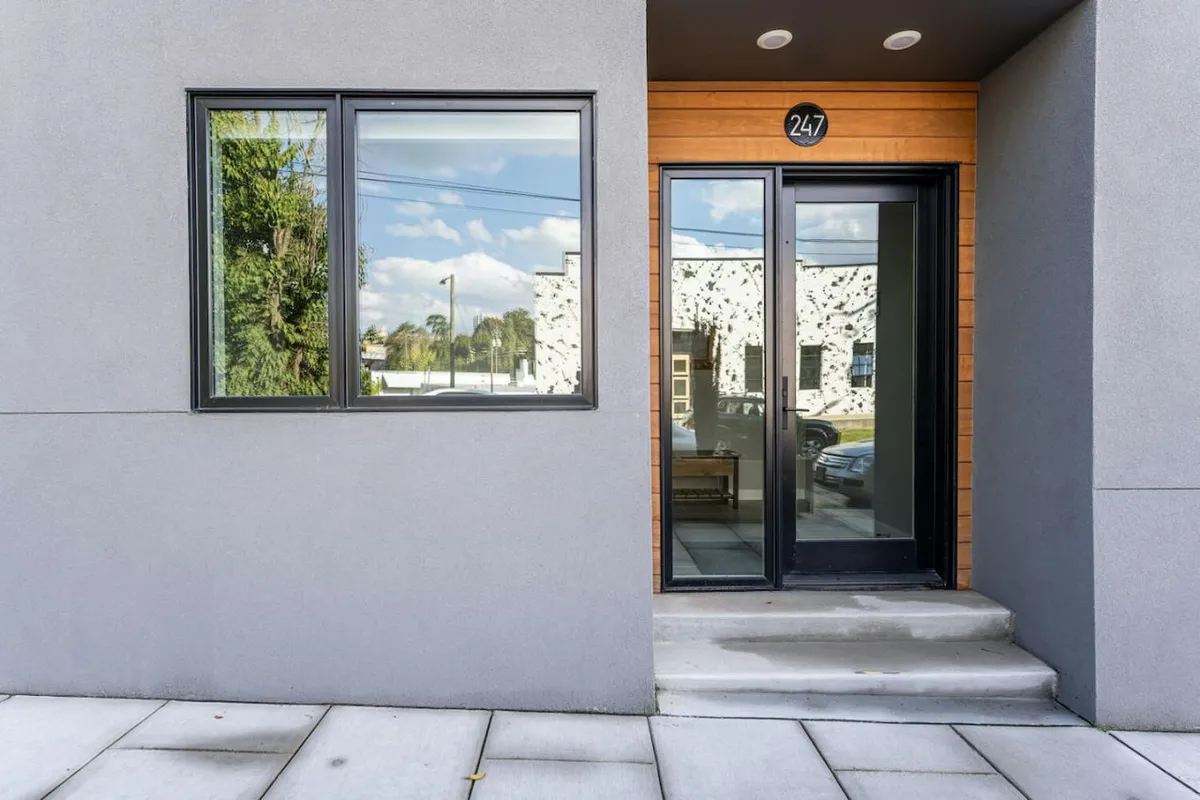 A striking modern exterior featuring a clean-lined door, expansive windows, and contemporary wood accents. The entrance is both stylish and inviting, setting the stage for a secure and welcoming arrival.