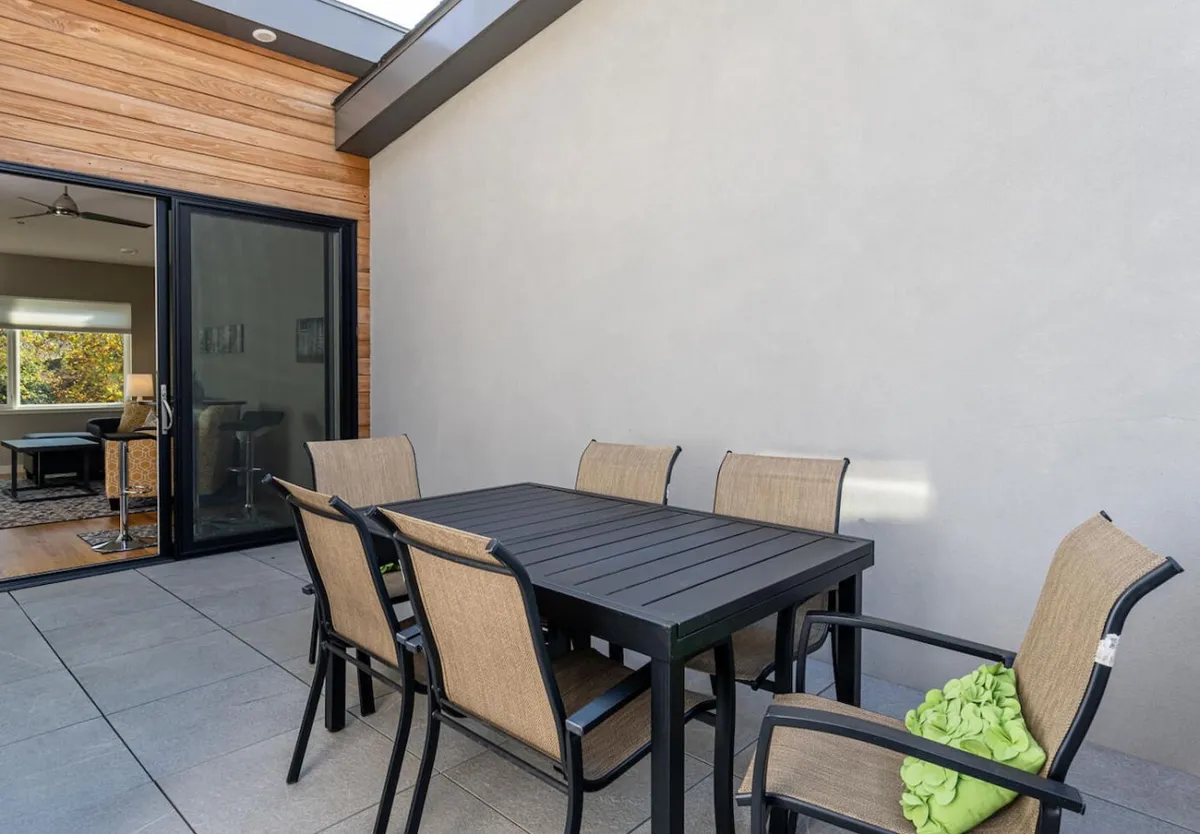 An inviting outdoor dining table with surrounding chairs bathed in natural light from an overhead skylight. The setup evokes leisurely meals shared in the fresh air, ideal for gathering after a day exploring local breweries and eateries.