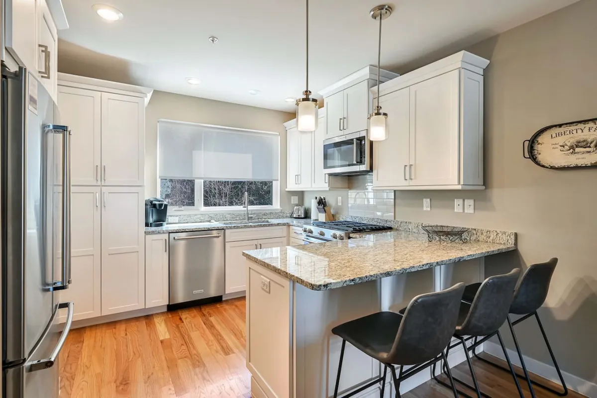 The kitchen is designed with a granite countertop and a spacious island, complemented by stainless steel appliances and pendant lighting. The layout encourages both culinary creativity and social interaction, making it ideal for cooking, entertaining, and intimate breakfasts.