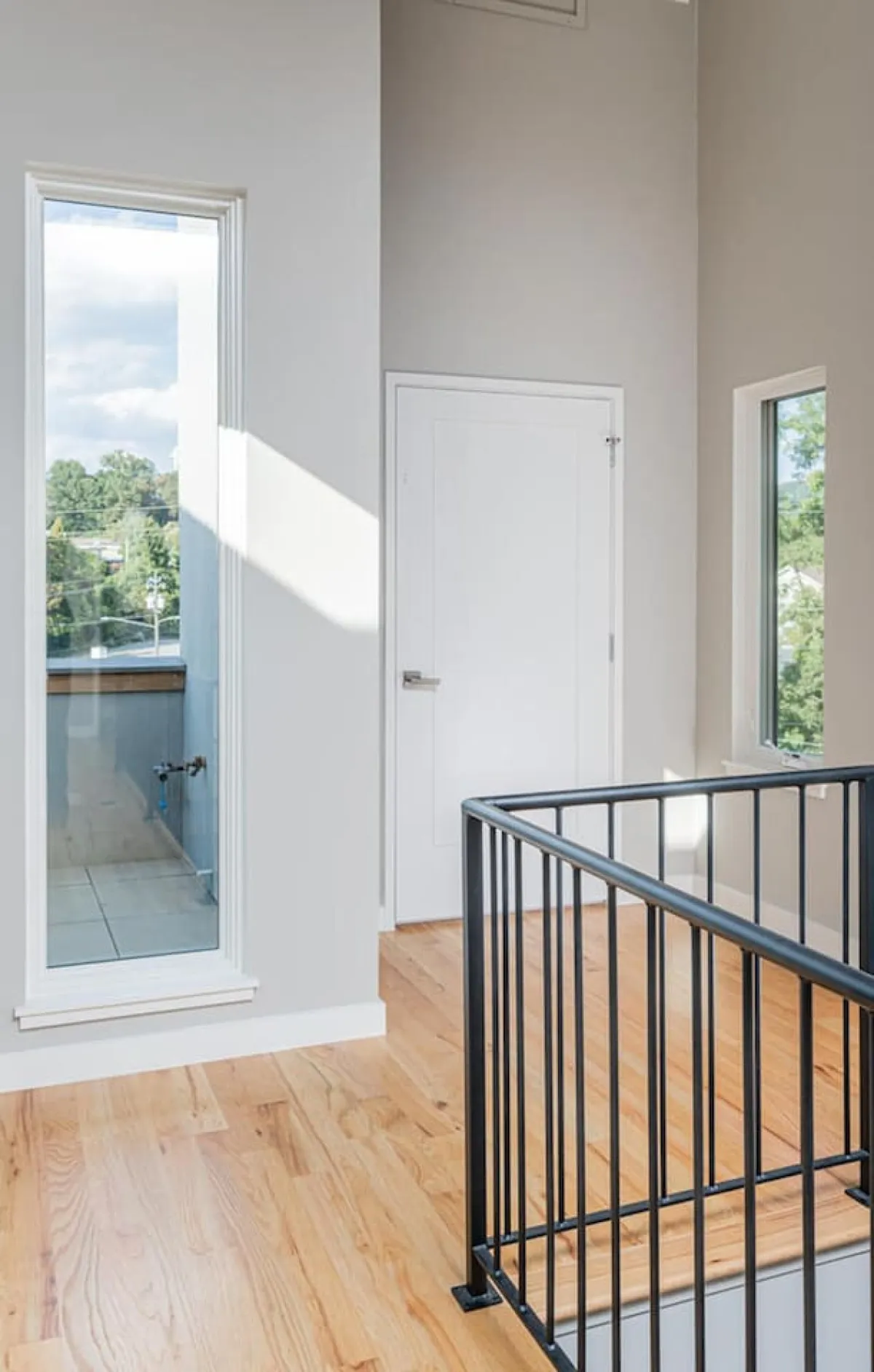 A bright interior scene highlights large windows, wooden flooring, and an open, airy space. Natural light floods the room, creating a serene environment that invites guests to relax, read, or enjoy the city views beyond.