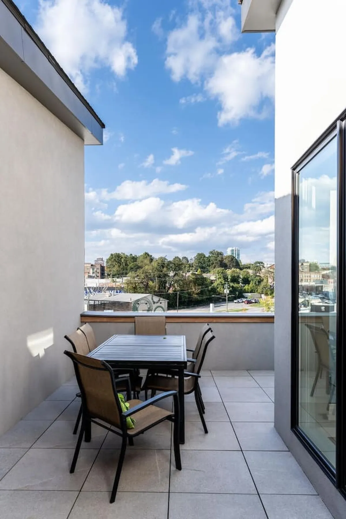 A stylish exterior dining area on the rooftop, with a table and chairs set against an open sky backdrop. The scene invites thoughts of relaxed outdoor meals and gatherings as the day turns to dusk, emphasizing both sunset and starlit experiences.